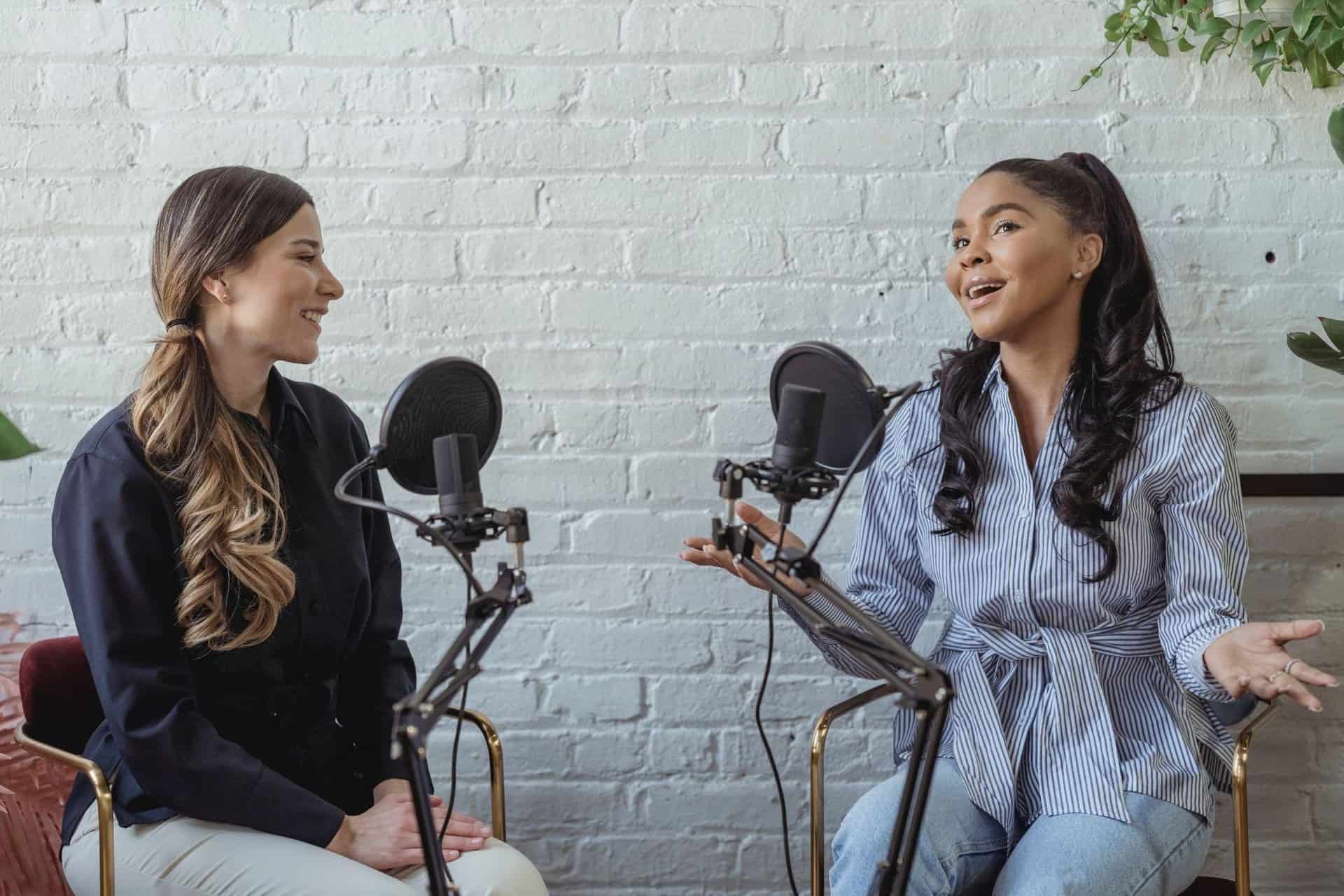 Two female hosts record a podcast