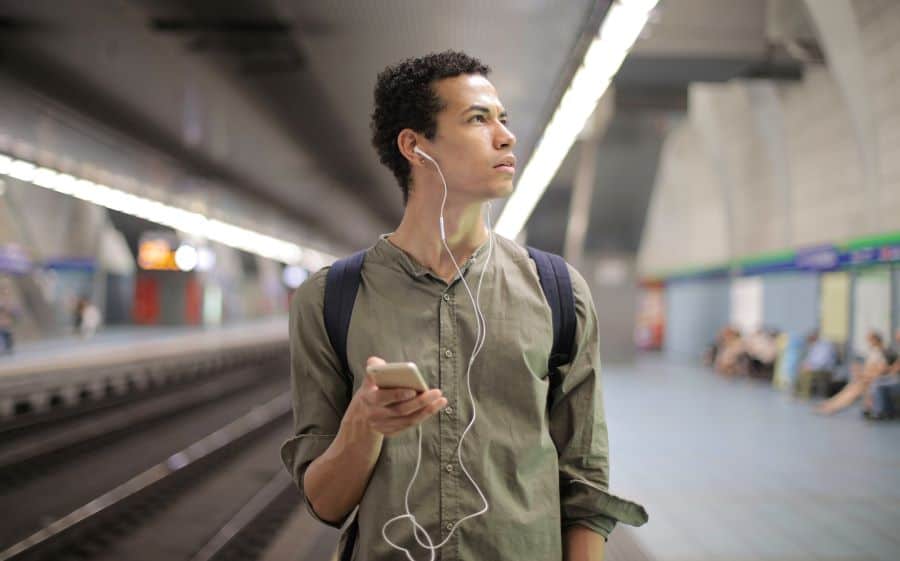 man listening to podcasts on train underground platform