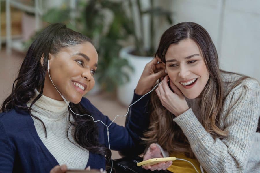 Two women listening to a podcast with the same headphones