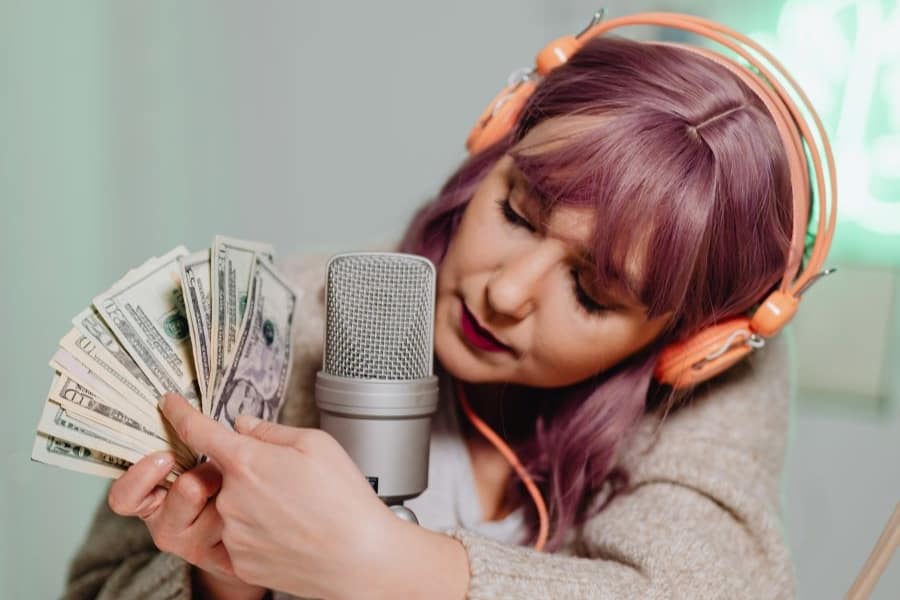 white woman showing money next to microphone