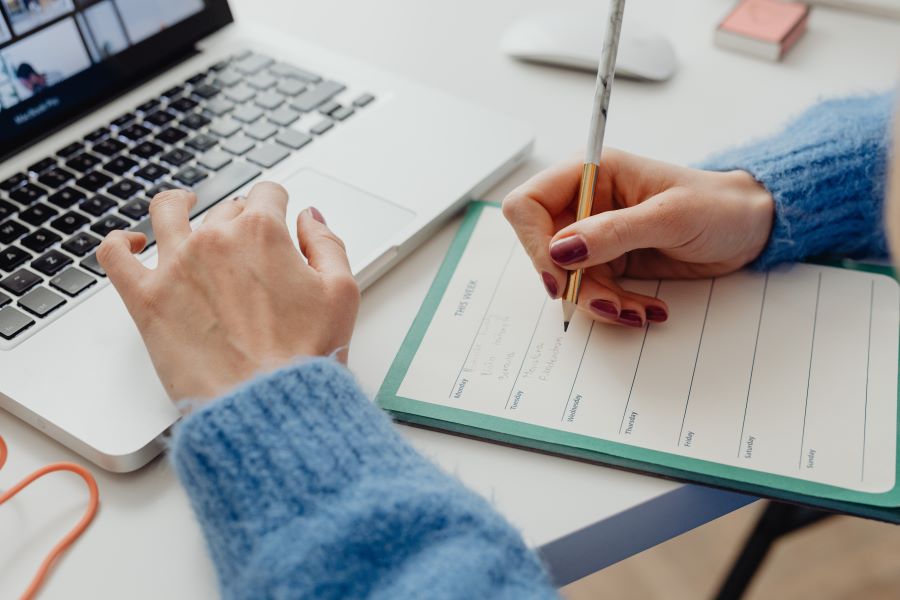 Person in Blue Long Sleeve Shirt Writing on White Paper