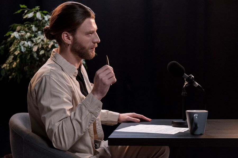 a man in beige long sleeve shirt interviewing a guest