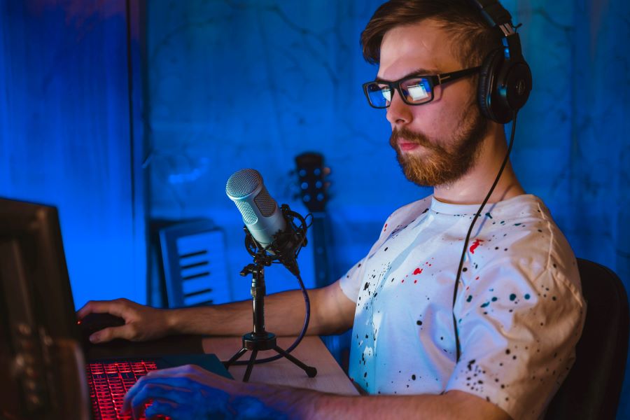 man in white shirt with splashy pattern working on a podcast