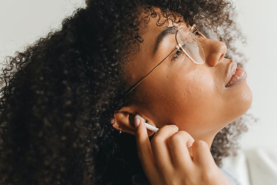 A Woman Wearing Eyeglasses Using Airpods