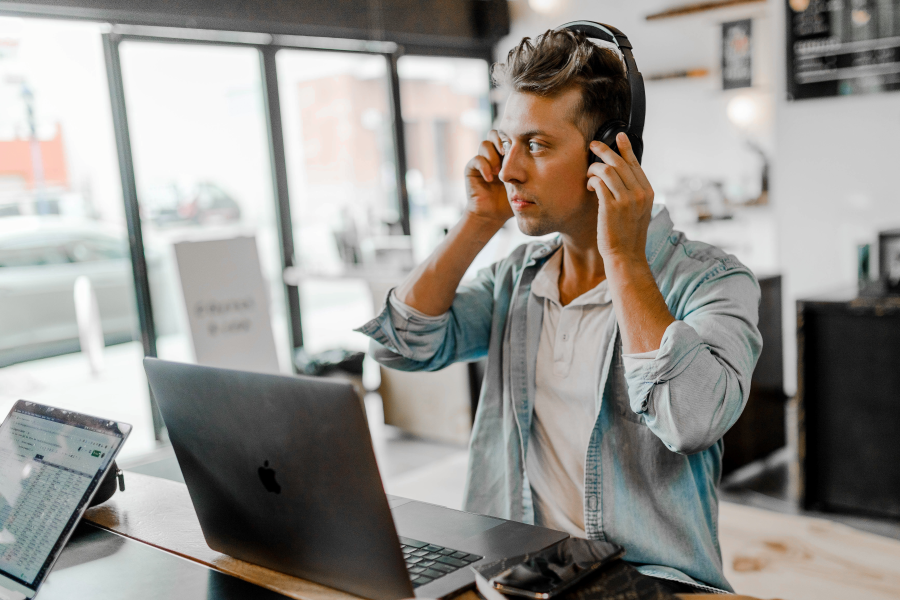 man wearing headphones while working at a macbook