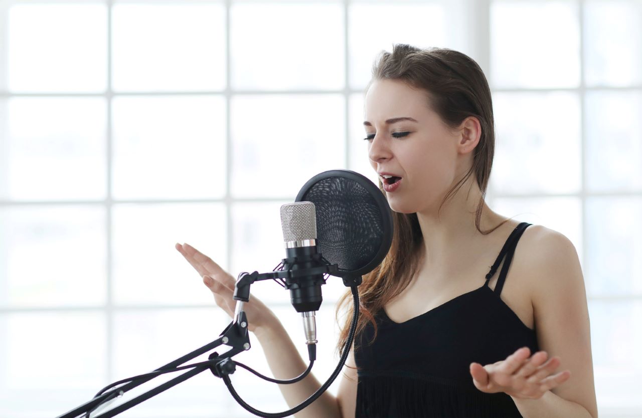 How to make your voice deeper on mic: Consider humming in a low pitch daily or practicing scales to gradually stretch and challenge your cords, resulting in a deeper resonance.